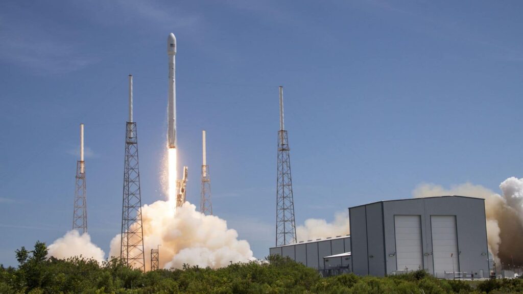 A rocket launching into the sky during the day, with smoke and flames highlighting advancements in satellite technology and IoT connectivity.