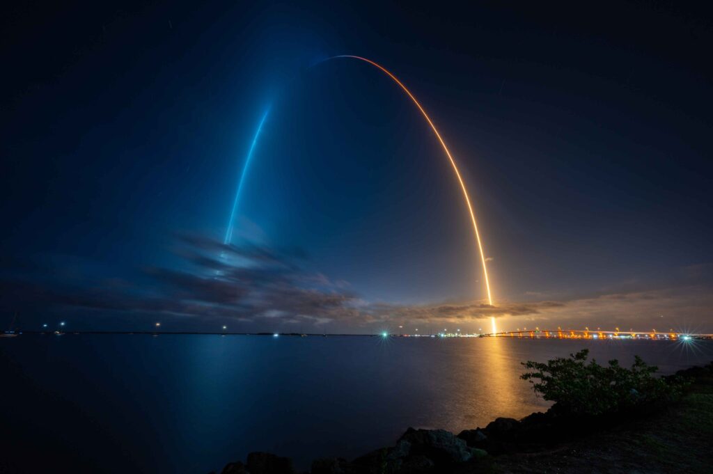 A stunning long-exposure photograph capturing the SpaceX Crew-2 launch from Titusville on April 23, 2021, with a luminous streak of light marking the rocket's trajectory. IoT connectivity supports mission-critical communication, enabling real-time monitoring and success of space exploration.