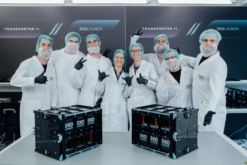 The Exolaunch and Sateliot teams posing together proudly with Sateliot's nanosatellite. IoT connectivity symbolizes their shared achievement in advancing satellite technology for seamless global communication.